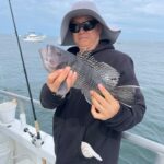 a person holding a fish on a boat in a body of water