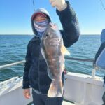 a person holding a fish in front of a body of water