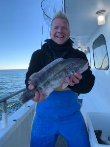 a man holding a fish on a boat in a body of water